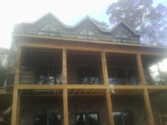 Dormers and porch framing on a large log home under construction — Roof Coating work by our crew in Picture Rocks