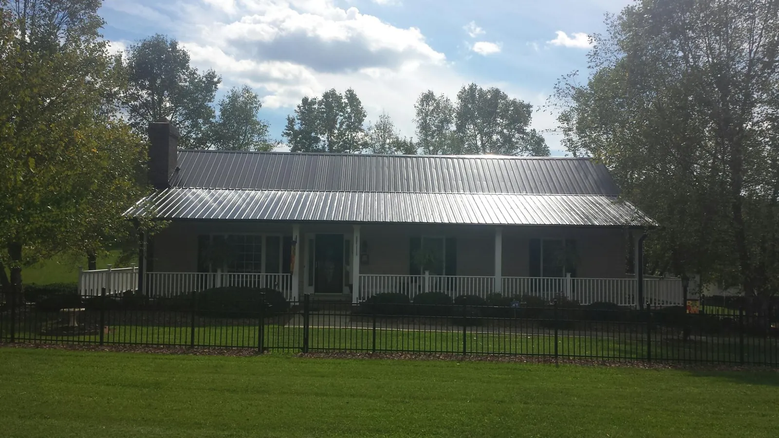 Gray metal roof on a brick ranch with a full width front porch — Gutter Guard Installation work by our crew in Picture Rocks