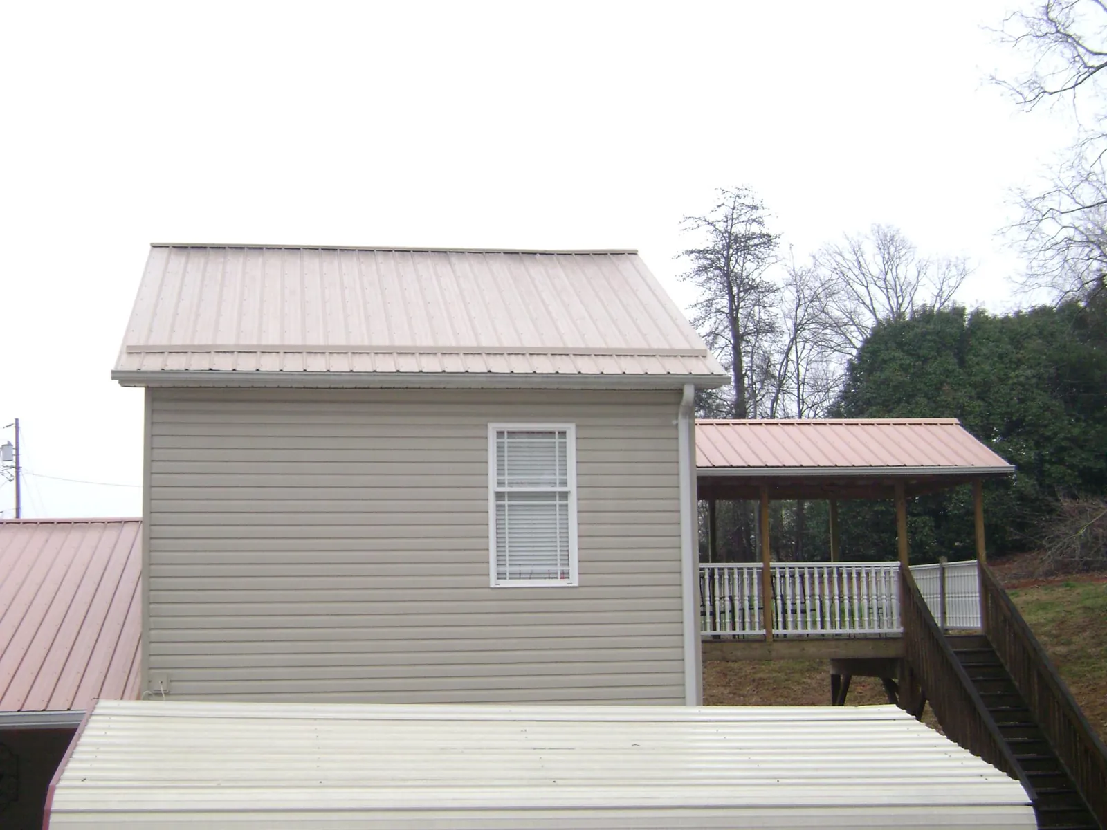 Tan metal roofs on a two story addition and attached porch, from a Roof Replacement job in Picture Rocks