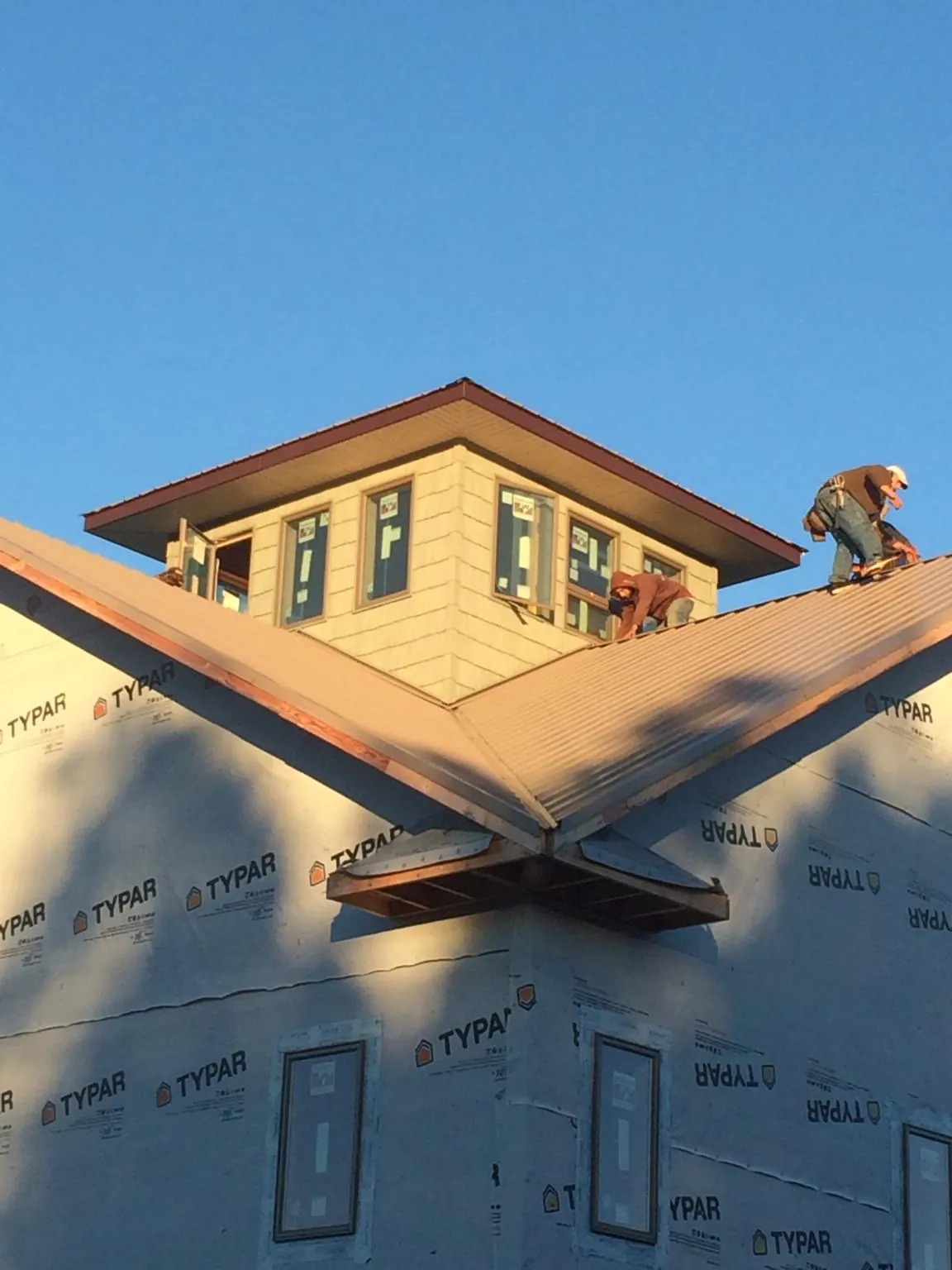 Roofers working around a rooftop cupola on a new metal roof at sunset — Roof Waterproofing in Picture Rocks by Roofing Brothers